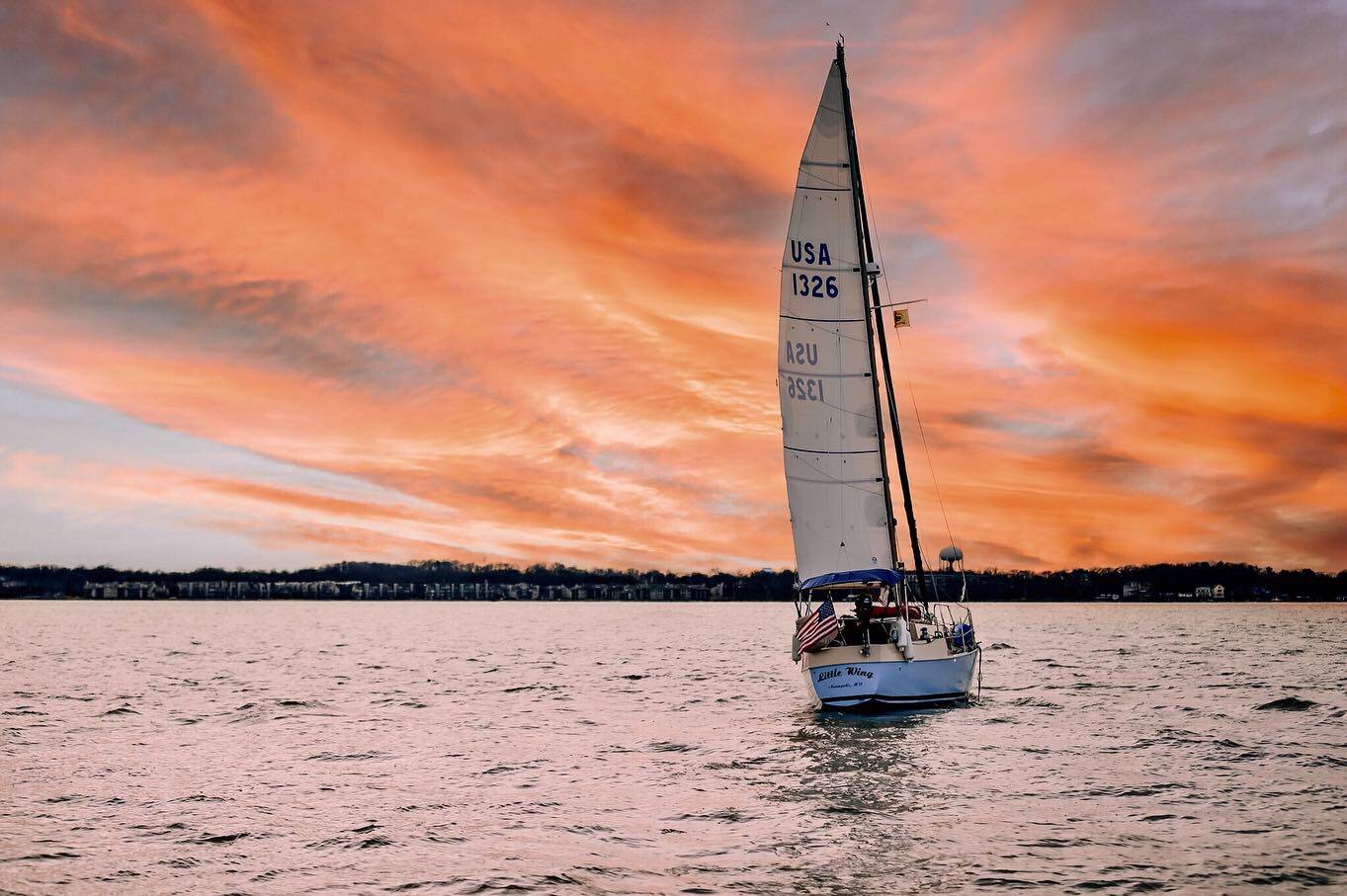 Kelsey Bonham '22 and her boat, Little Wing, in the sunset.