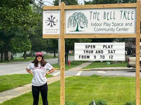 Corey McLaughlin stands next to a sign for the Bell Tree