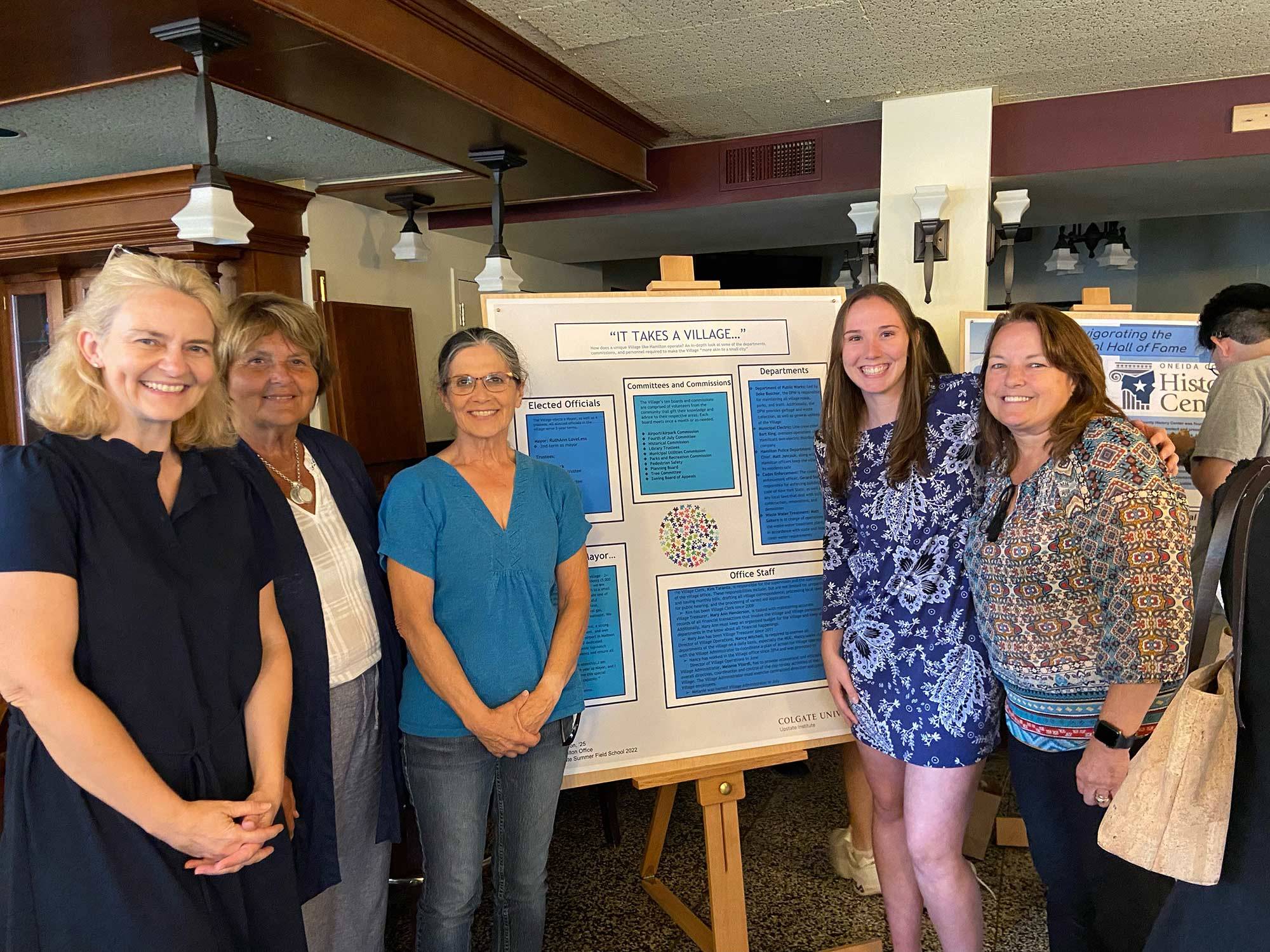 Morgan stands in front of her research poster with village officials