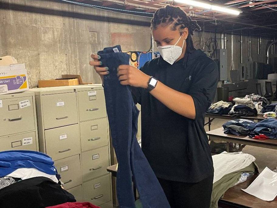 Tiasia McMillan folds a pair of jeans in the clothing storage room of the Center