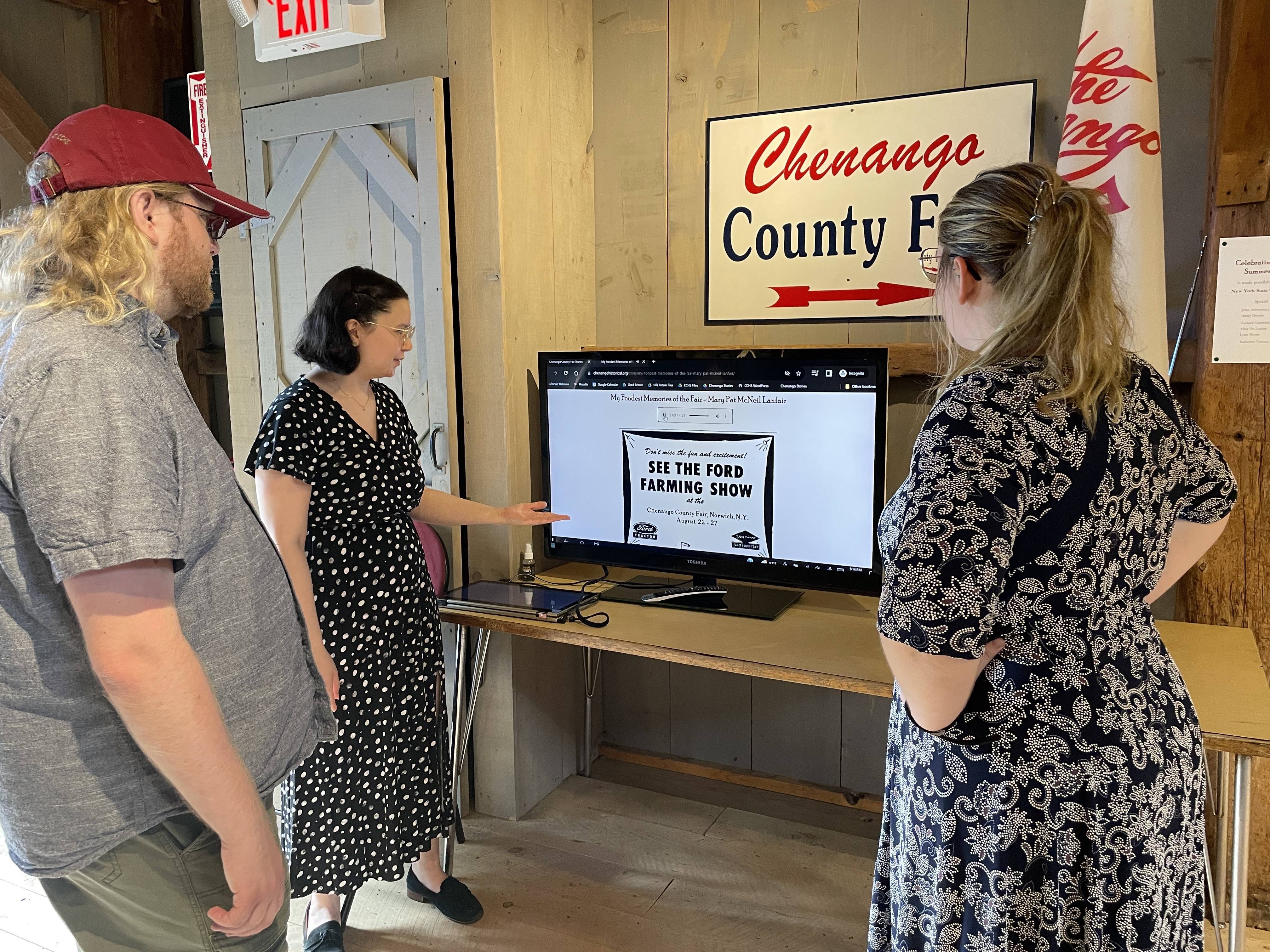 Marisa Modugno shows visitors a monitor that displays an oral history of the Chenango County Fair