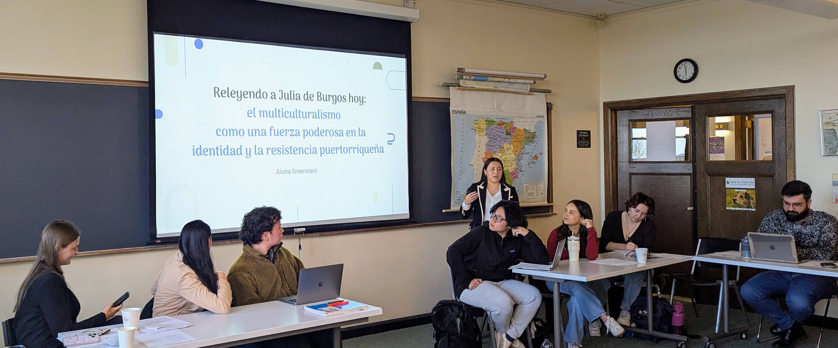 Presenter with students looking on.