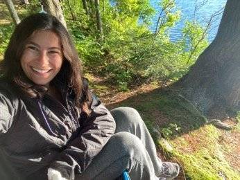 Natalie seated next to a pond in the Adirondacks