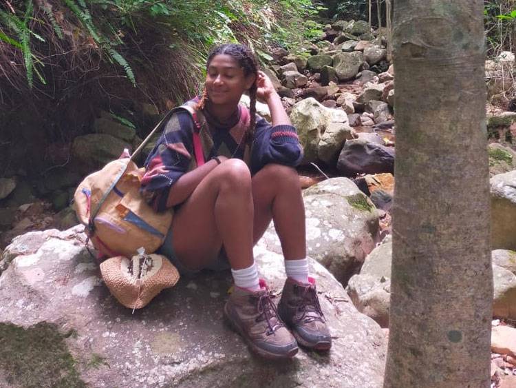 Sarafina Lewis sitting on a rock in the forest.