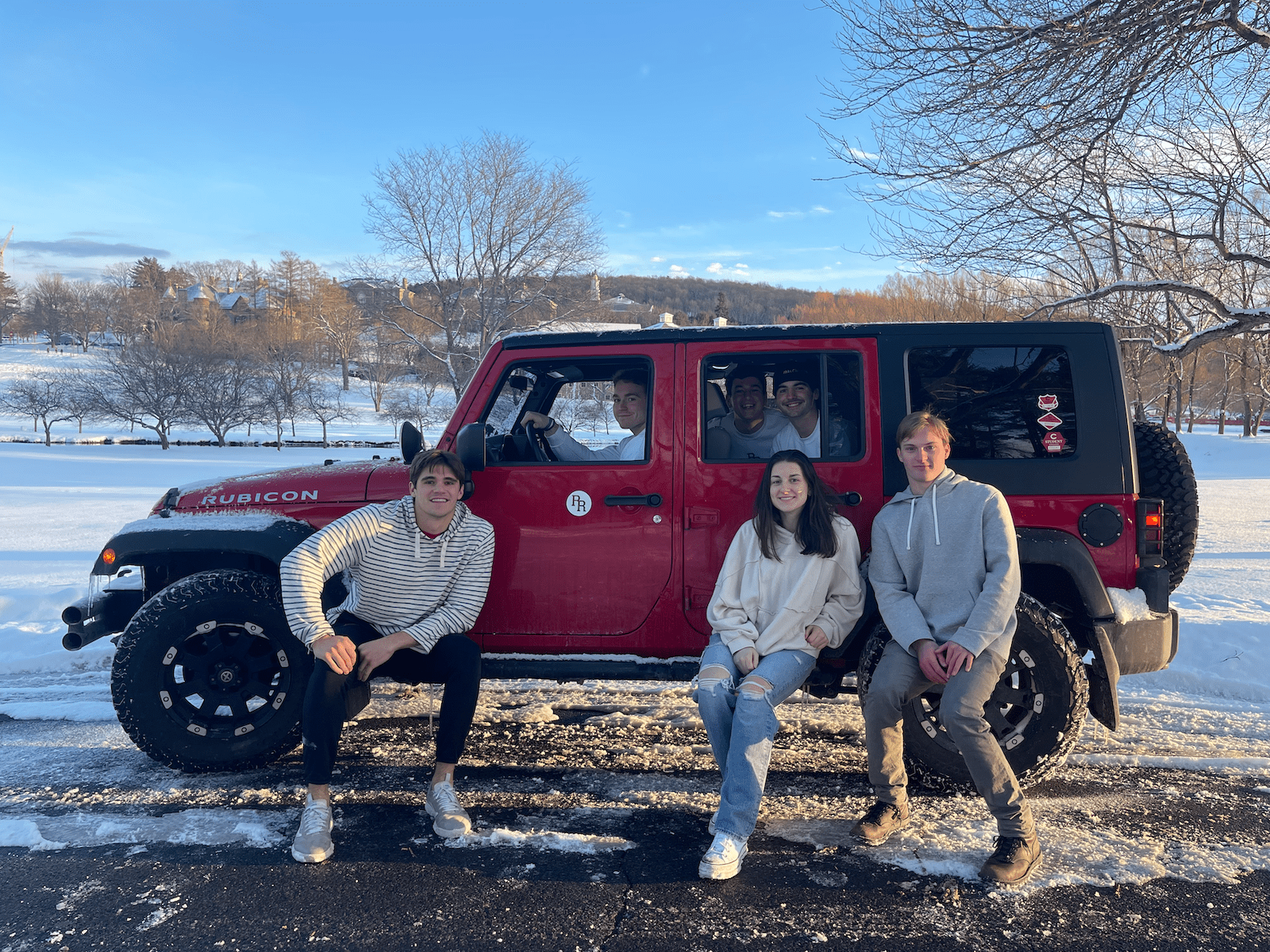 Group of people surrounding a red jeep