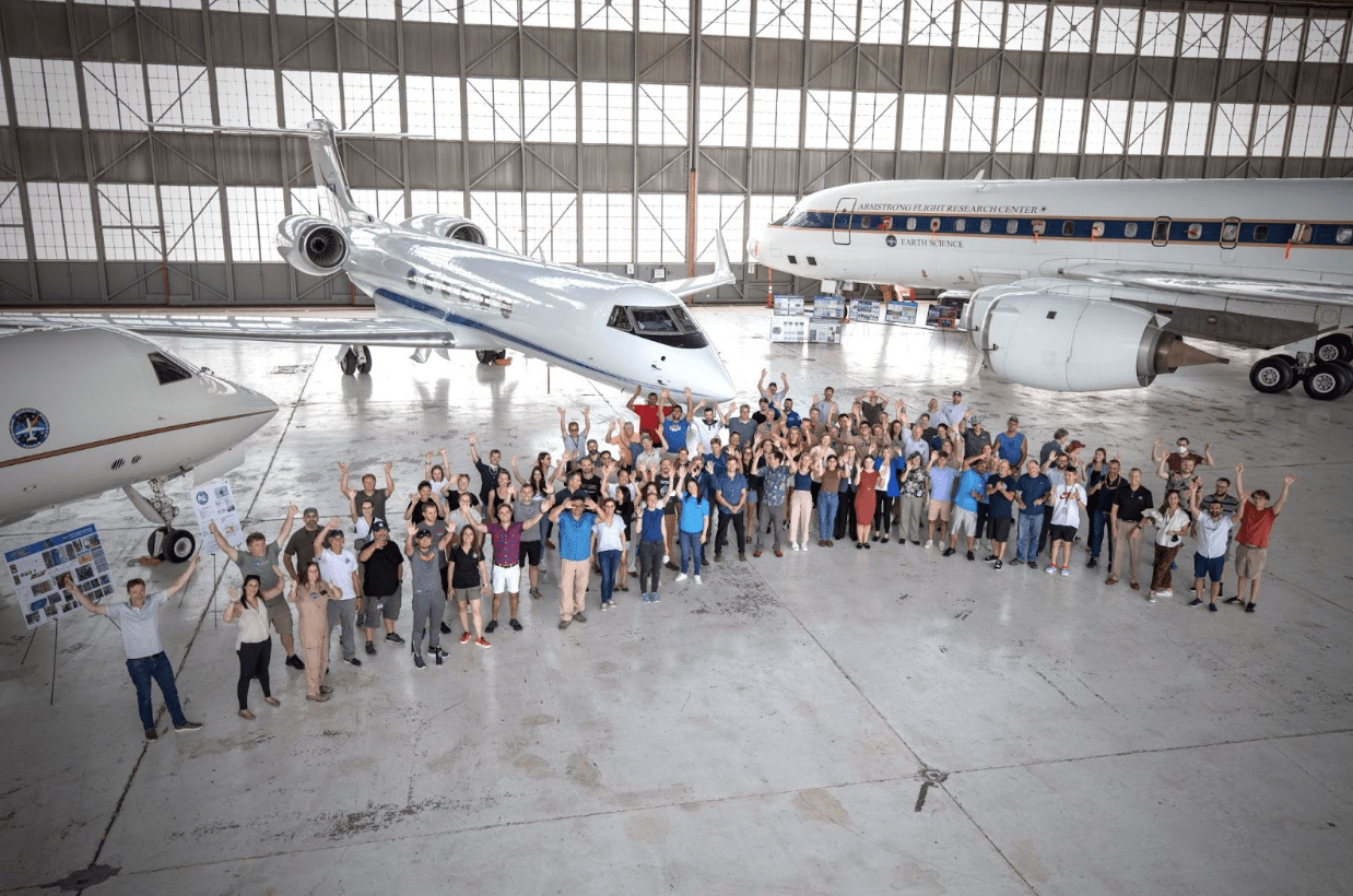 Photo of large group of researchers standing in front of a white research plane.