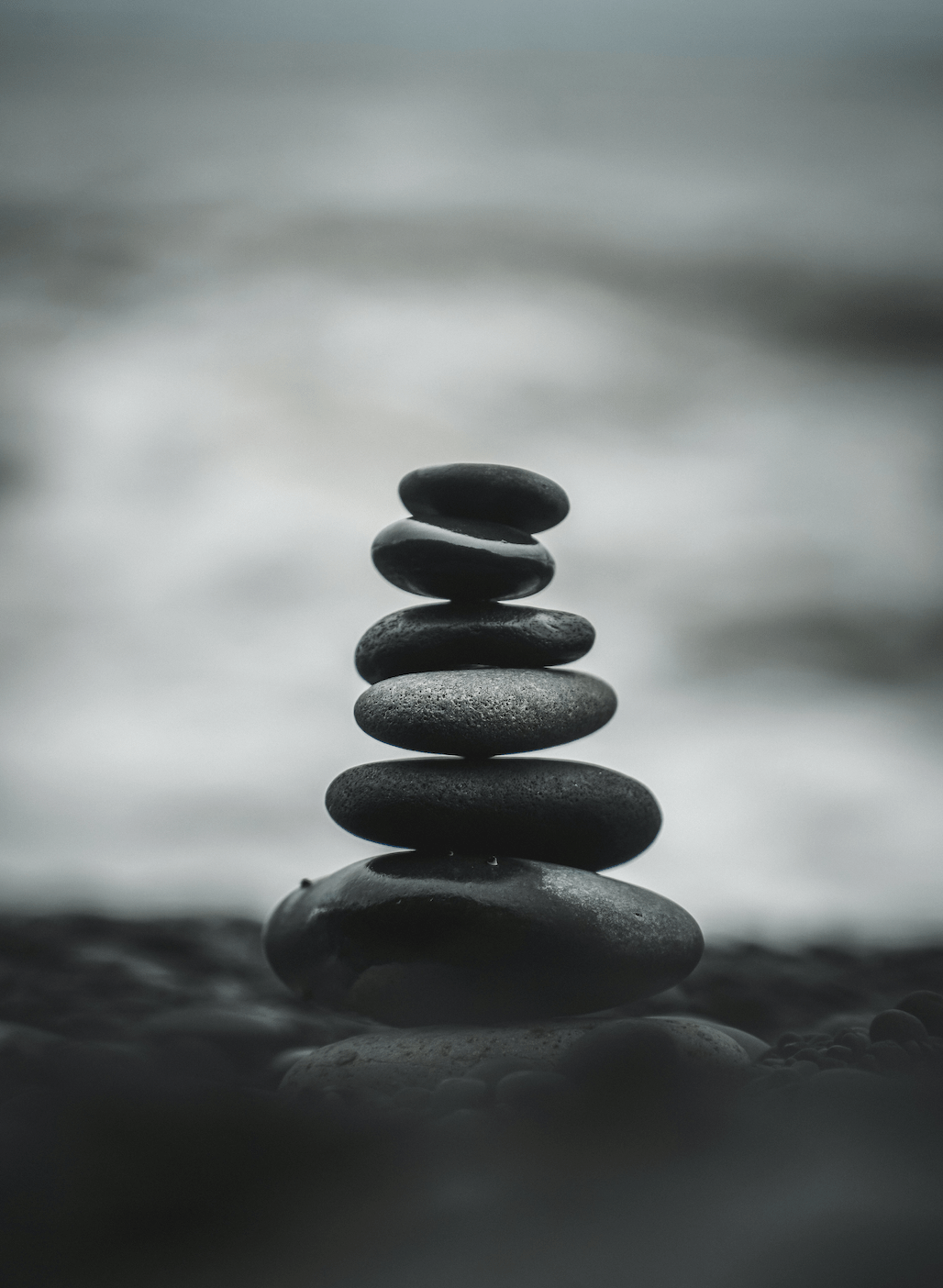 A stack of rocks sits balanced against a shoreline. 