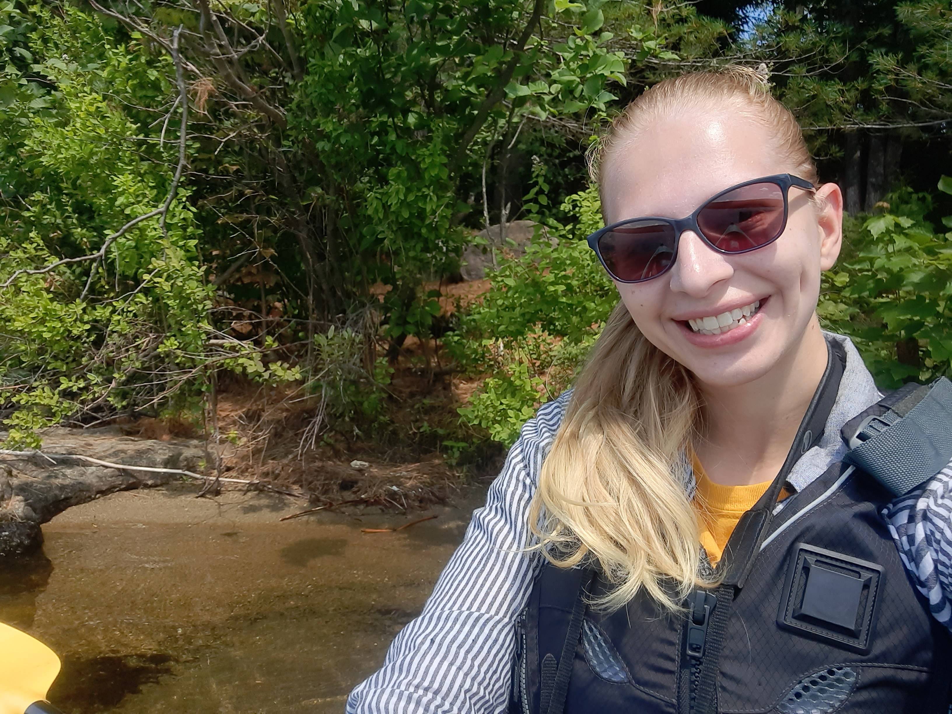 Tessa is in a kayak on a lake in the Adirondacks