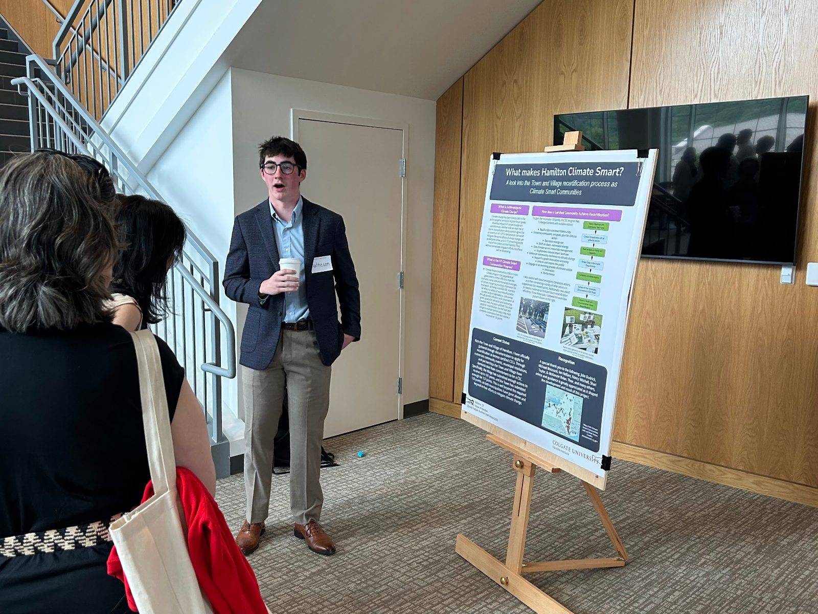 Matheson Williams ’27 stands with his poster outlining his research project with the Town and Village of Hamilton.