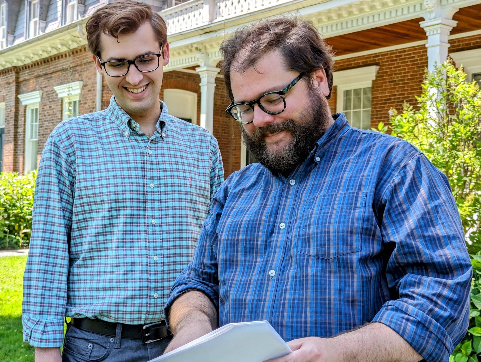 Eli Watson stands with Tom Guiler outside the Mandsion House and reviews a document