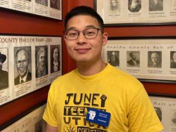 Ray stands in front of photos of individuals inducted in the Hall of Fame