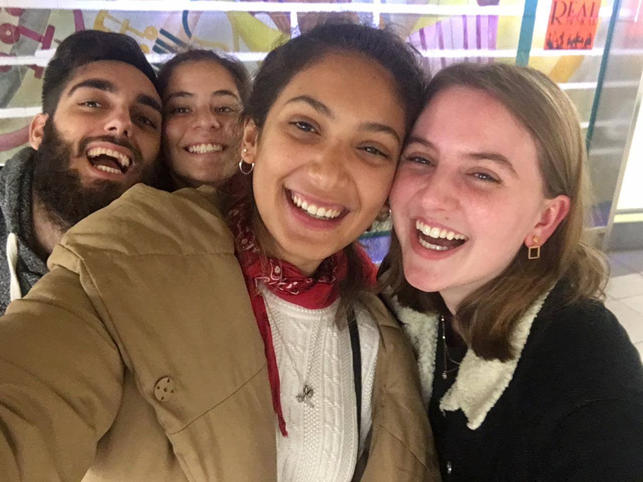 Two girls laughing together with two smiling people peering over their shoulders