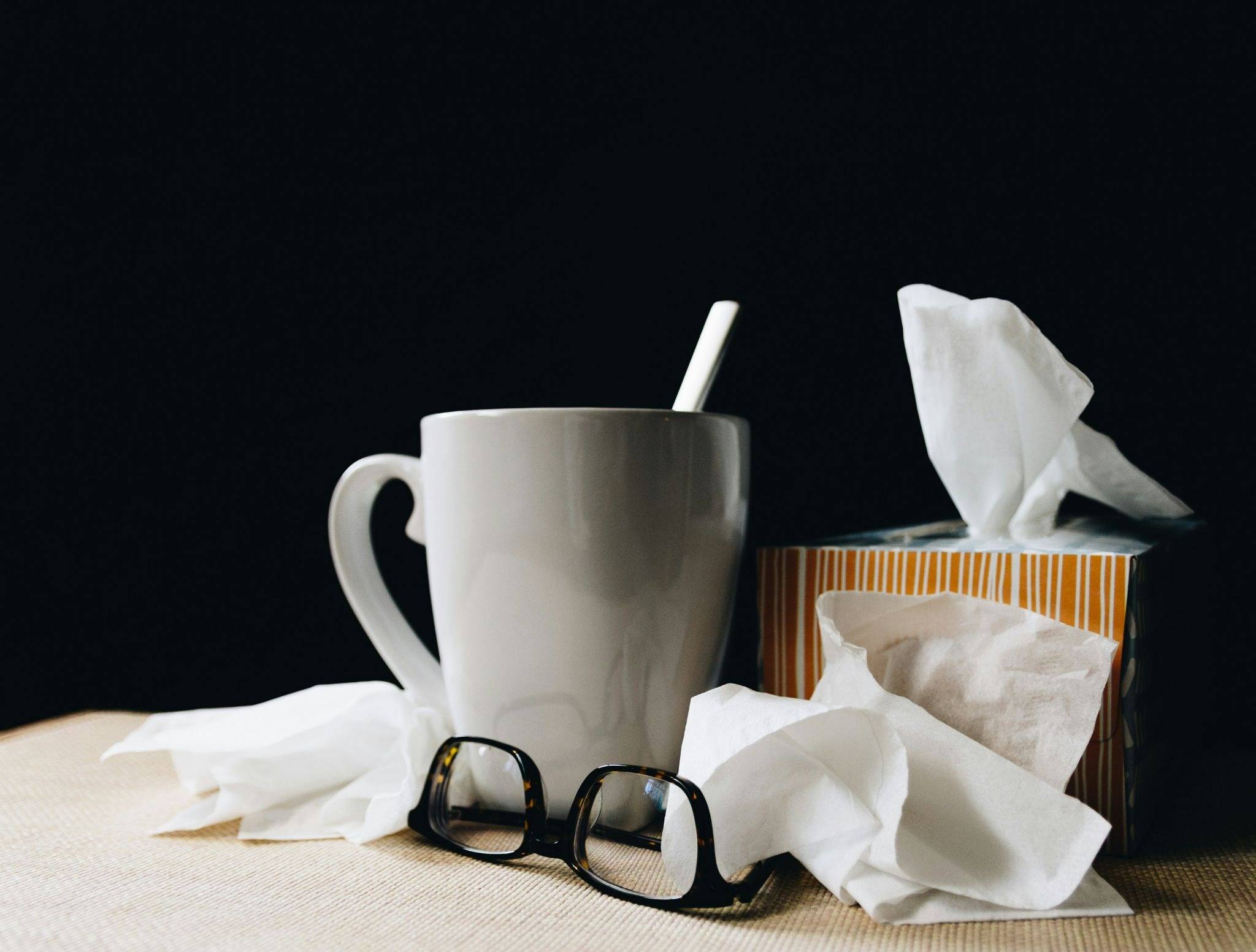Glasses, tissue and cup of tea shown to symbolize things someone may have sitting nearby when sick