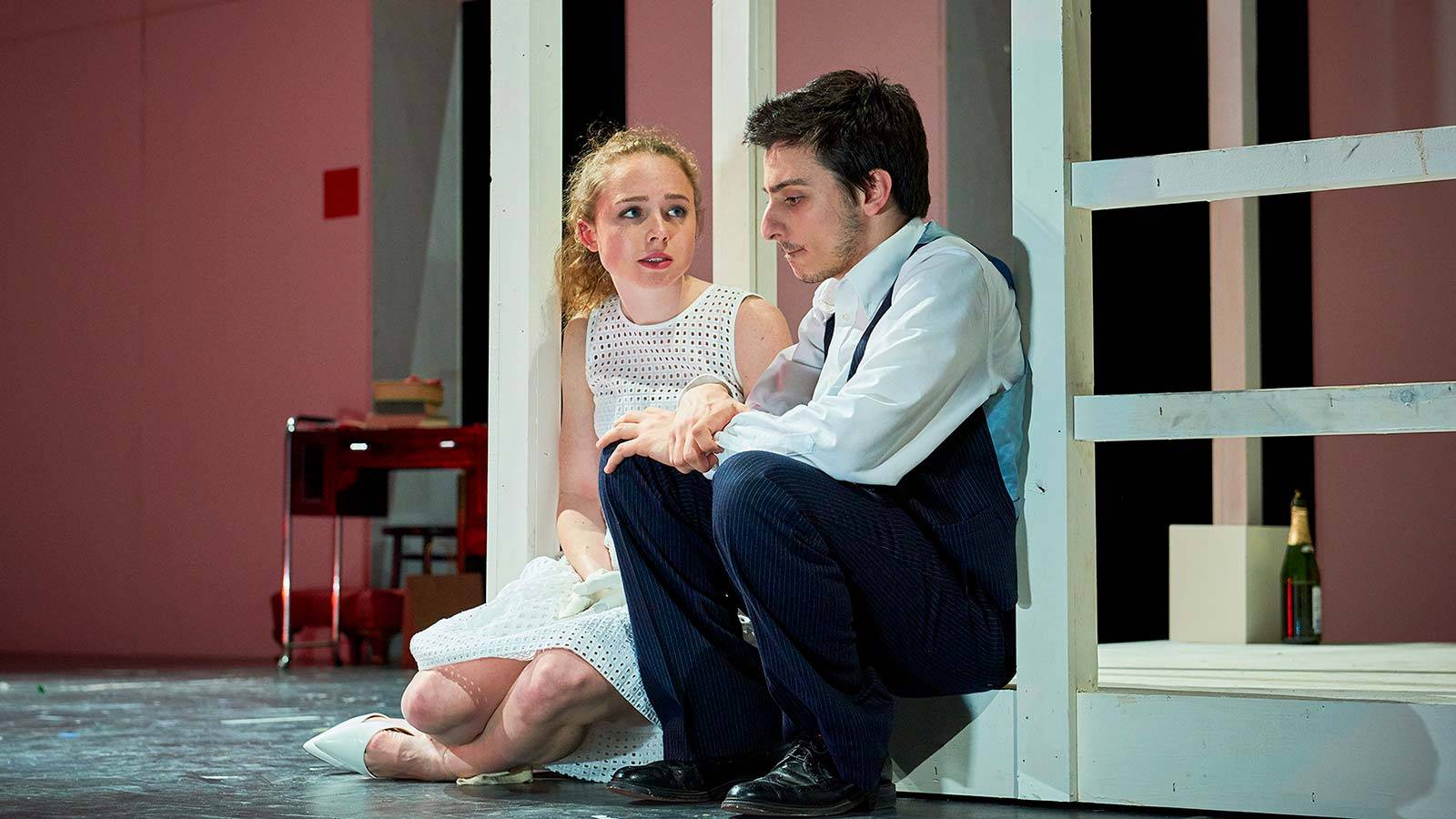 A male and female actor sit on stage engaged in an intense conversation