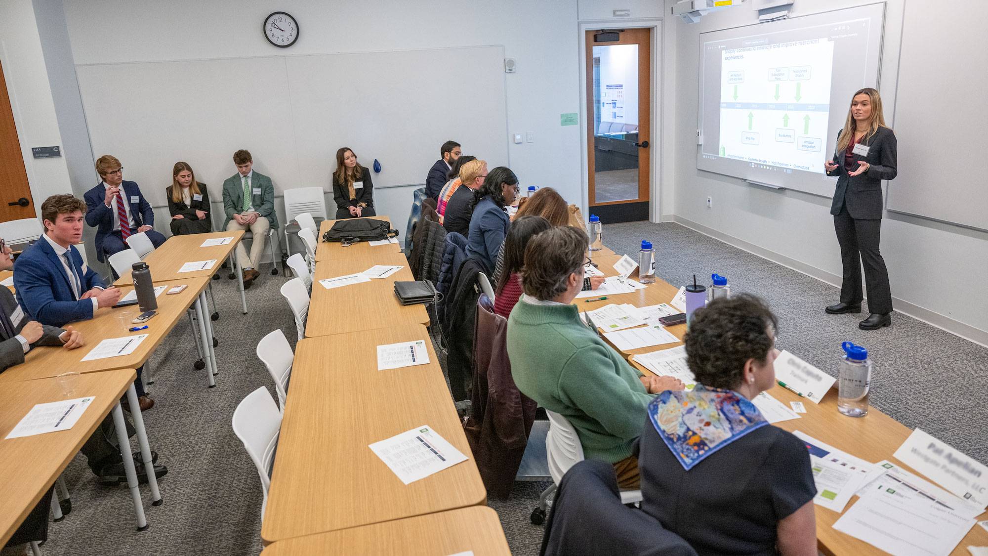 Student stands at white board and delivers presentation