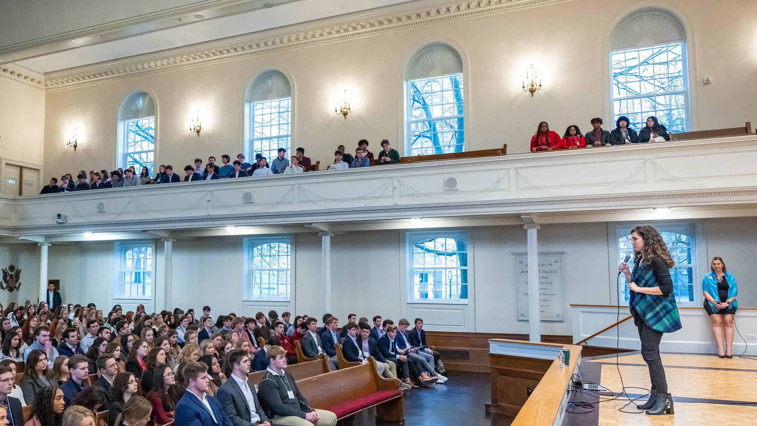 Students listen to speaker who stands on stage