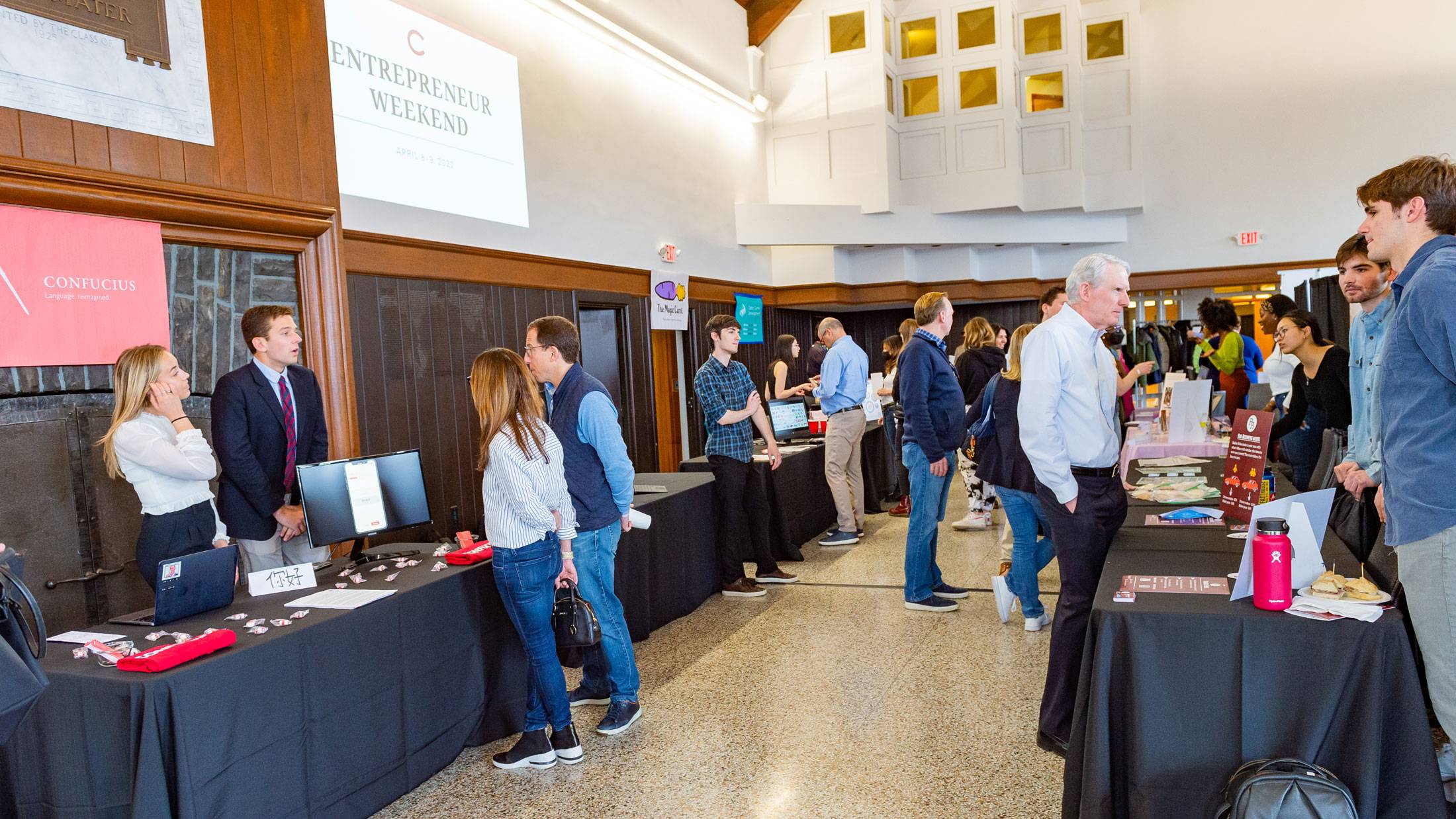 Entrepreneur Weekend attendees stand at tables talking with entrepreneurs