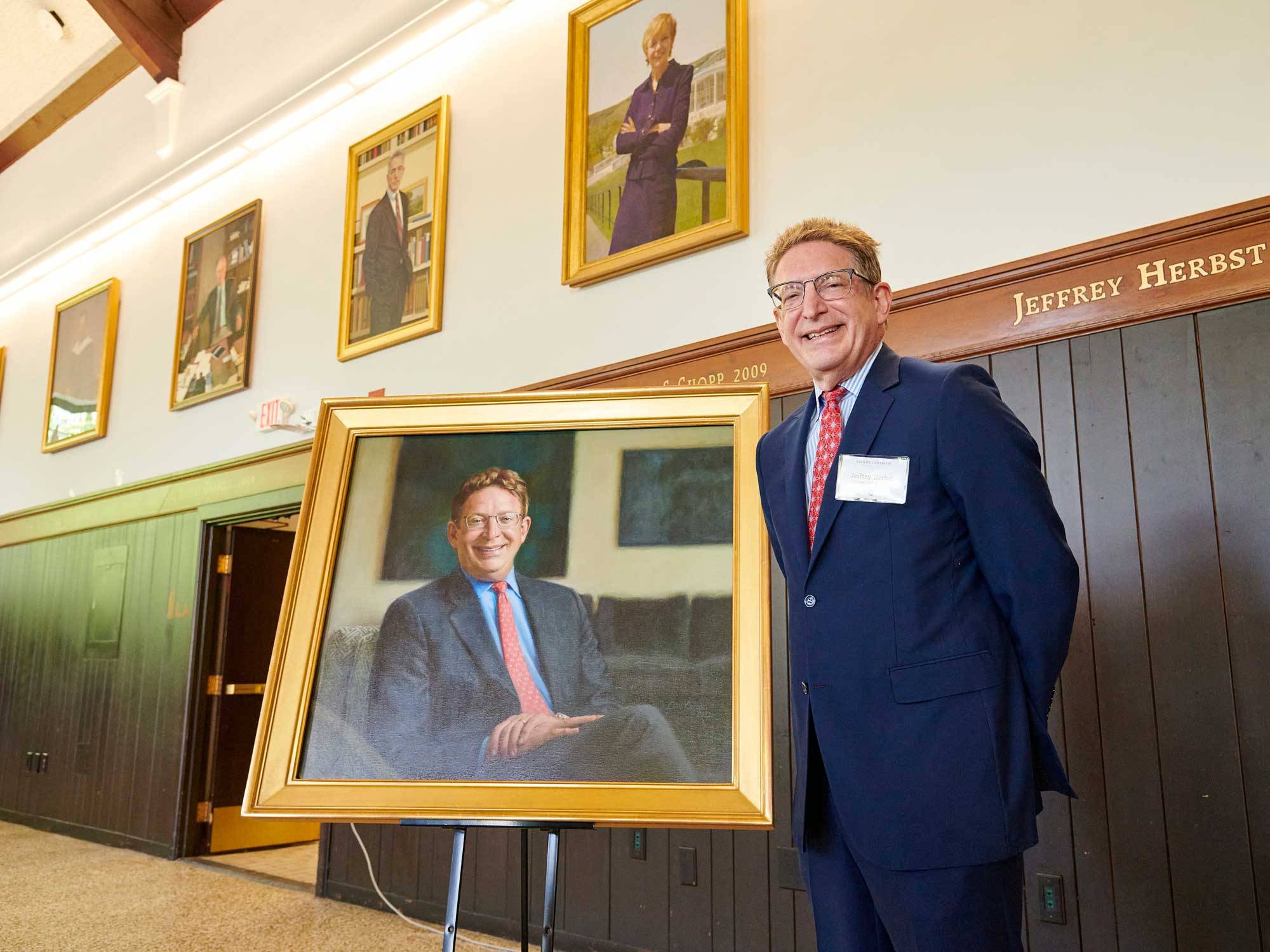 Jeffrey Herbst stands next to his new portrait
