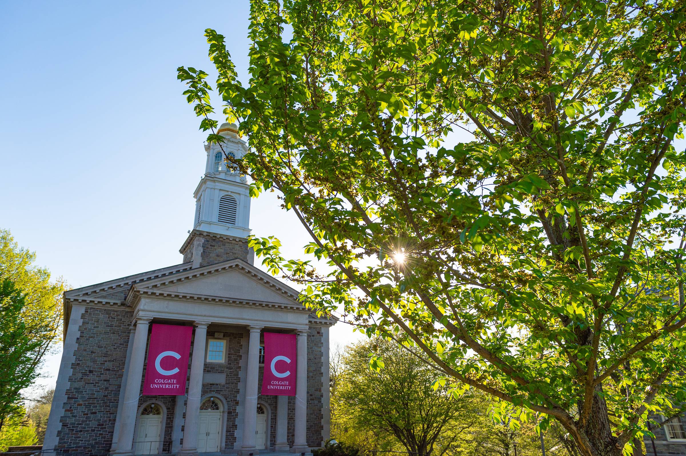 The chapel cloaked in sunlight, maroon banners, and summer greenery.