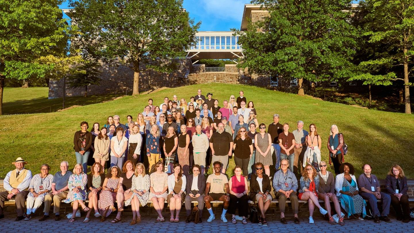 Writers conference participants pose together in front of the Persson Hall bridge