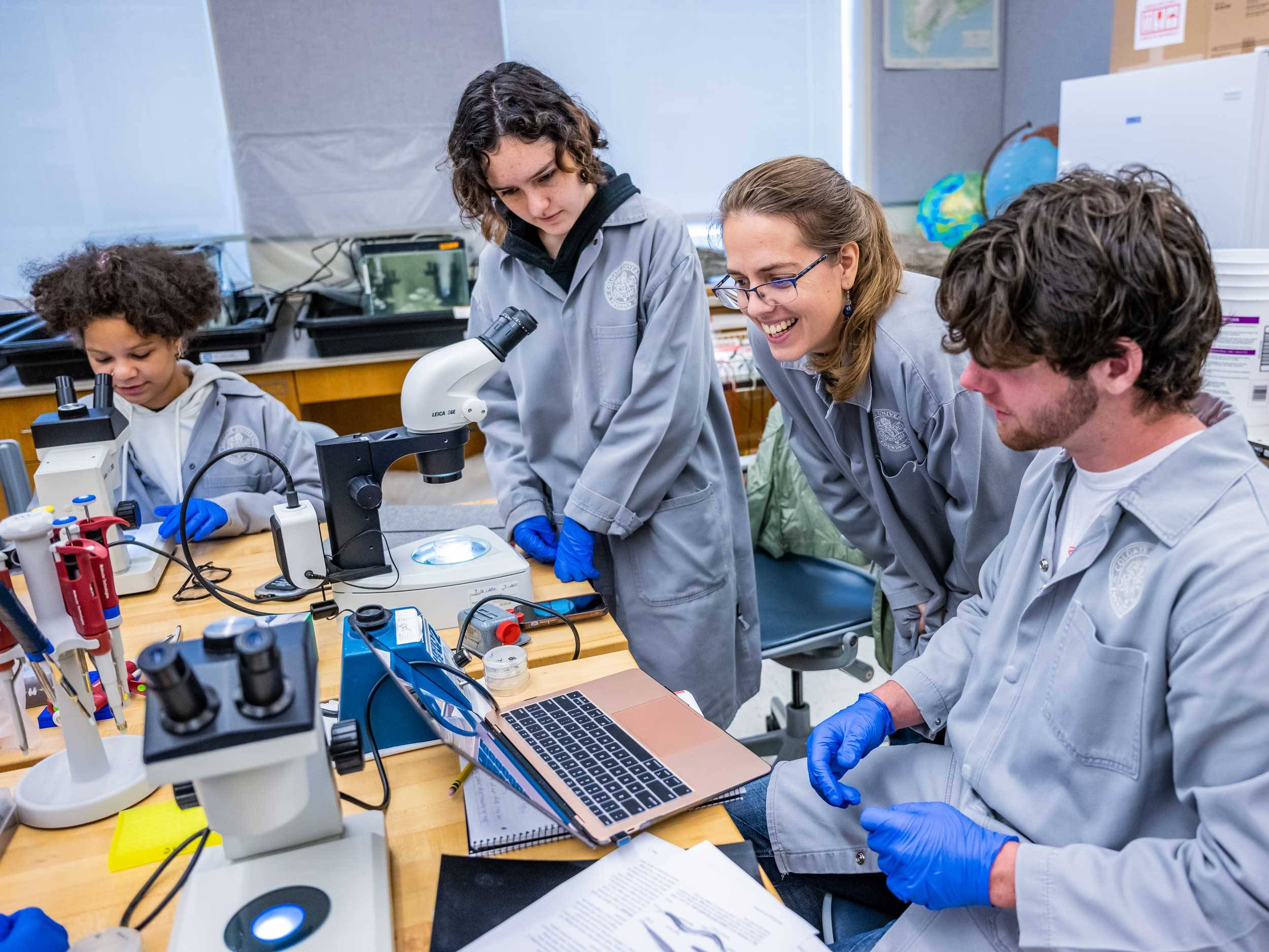 Students and professor look through microscope