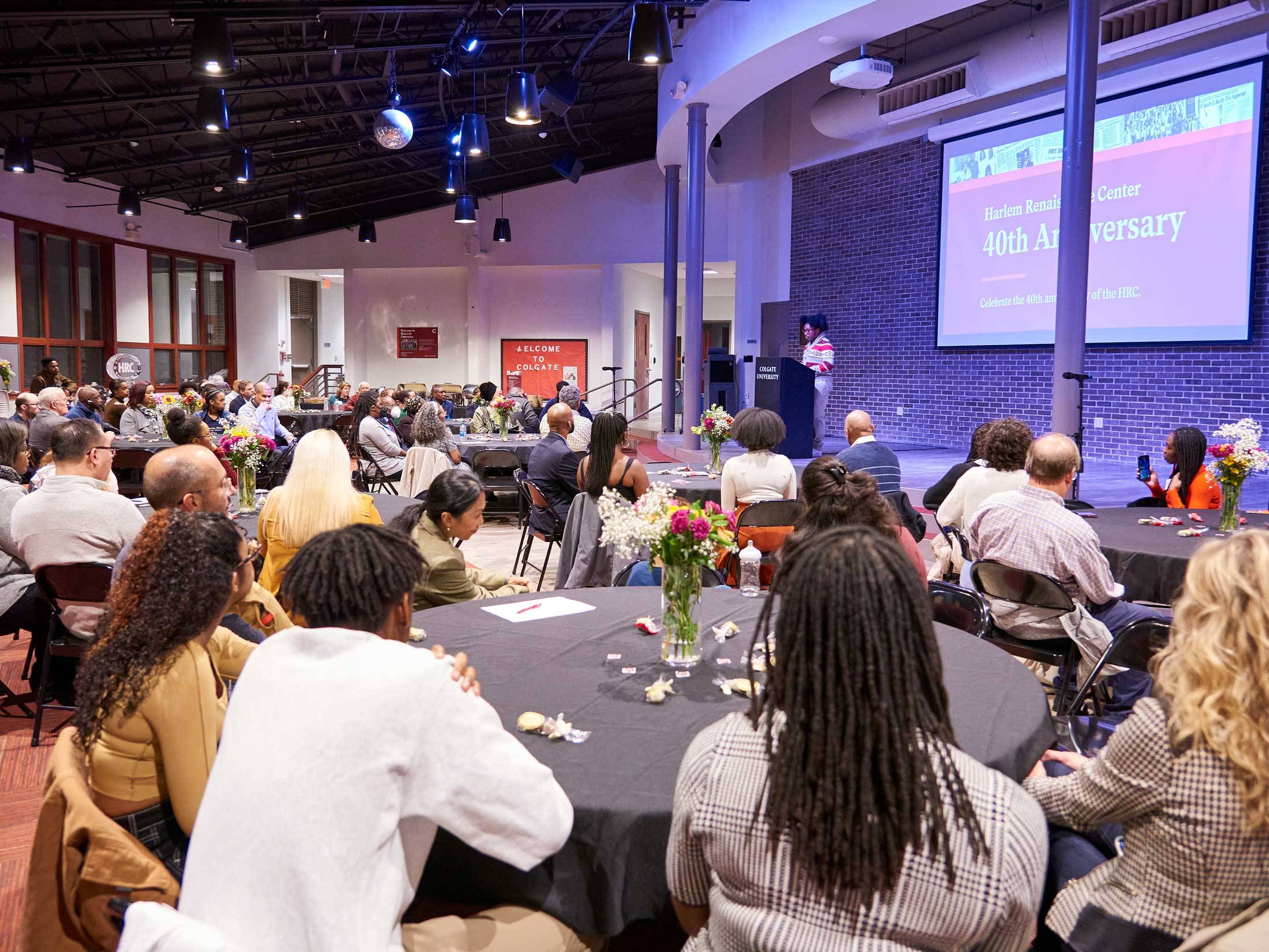 Attendees sit at tables listening to speech