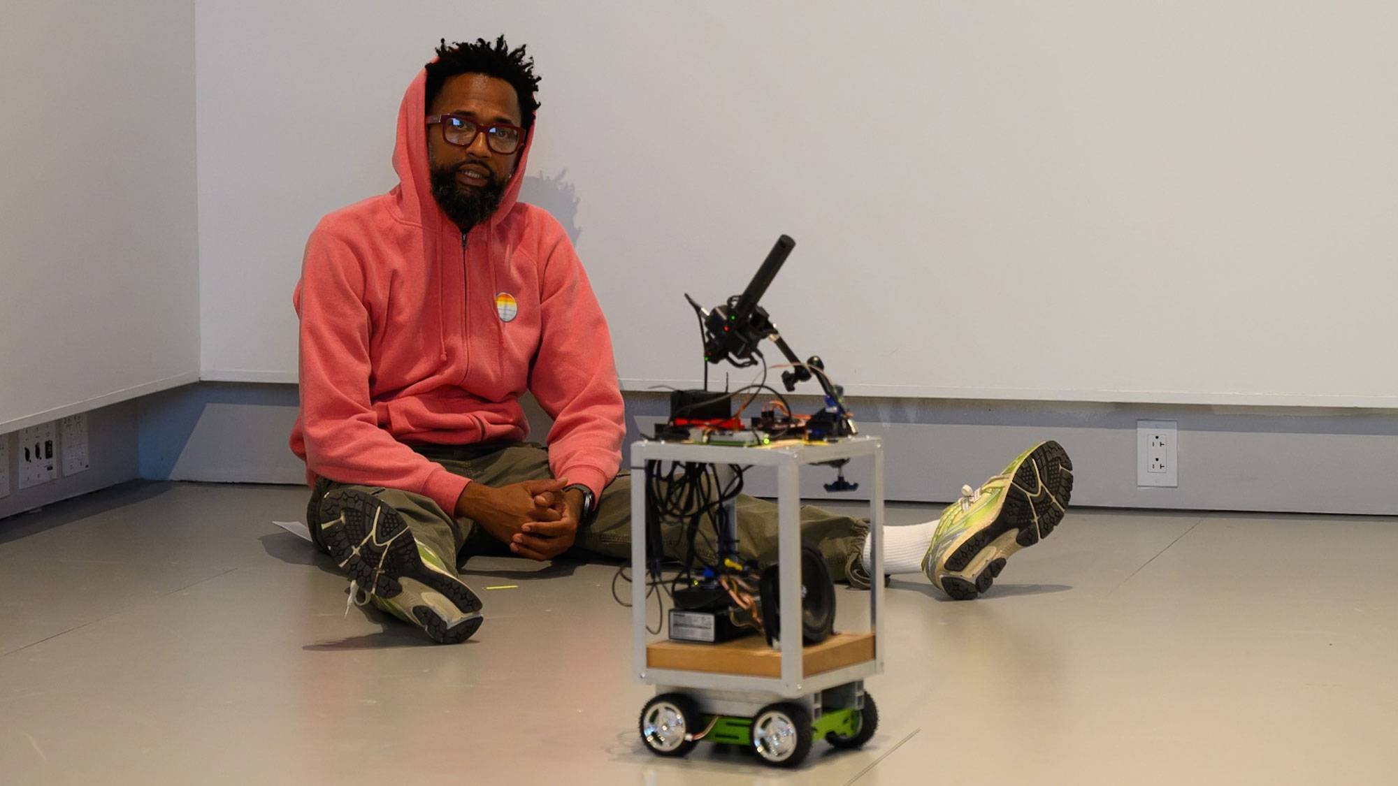 Actor sits on floor next to robot