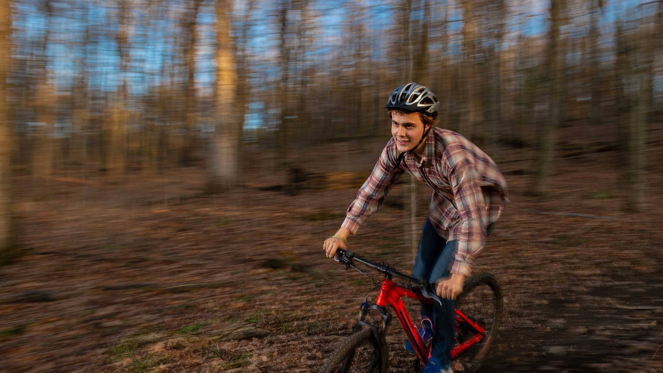 Jacob Watts rides bike on campus trails