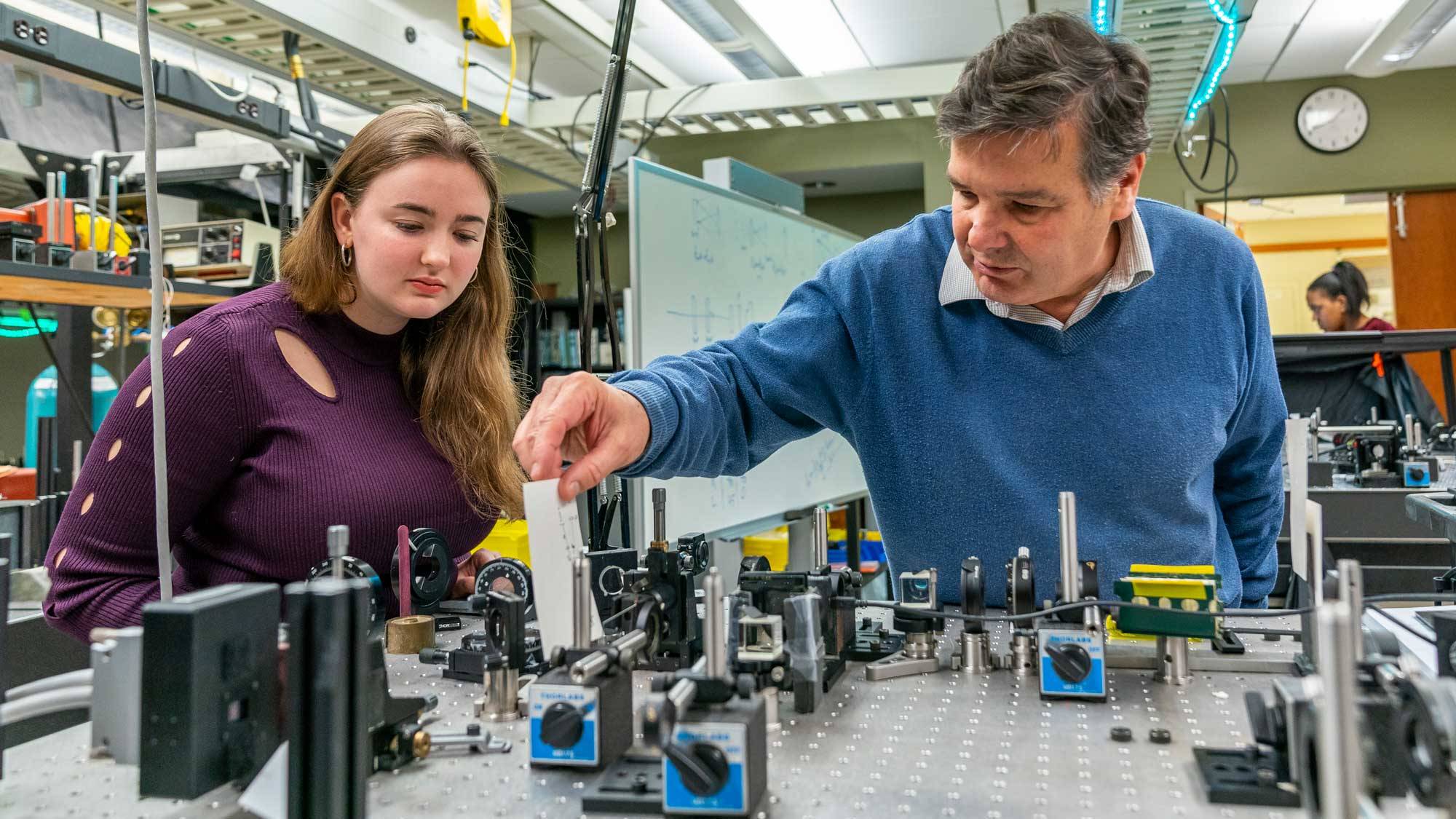 Prof. Kiko Galvez stands over table with lasers and reflectors