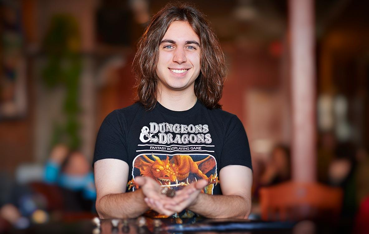 Ian Dwyer ’14 in a Dungeons and Dragons t-shirt holding playing dice.