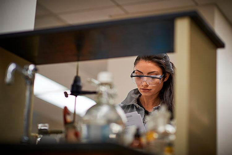 Student stands at a lab table, reading notes in Wynn Hall