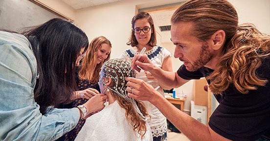 Professor Bruce Hansen works with students to prepare a test subject for a brain scan.