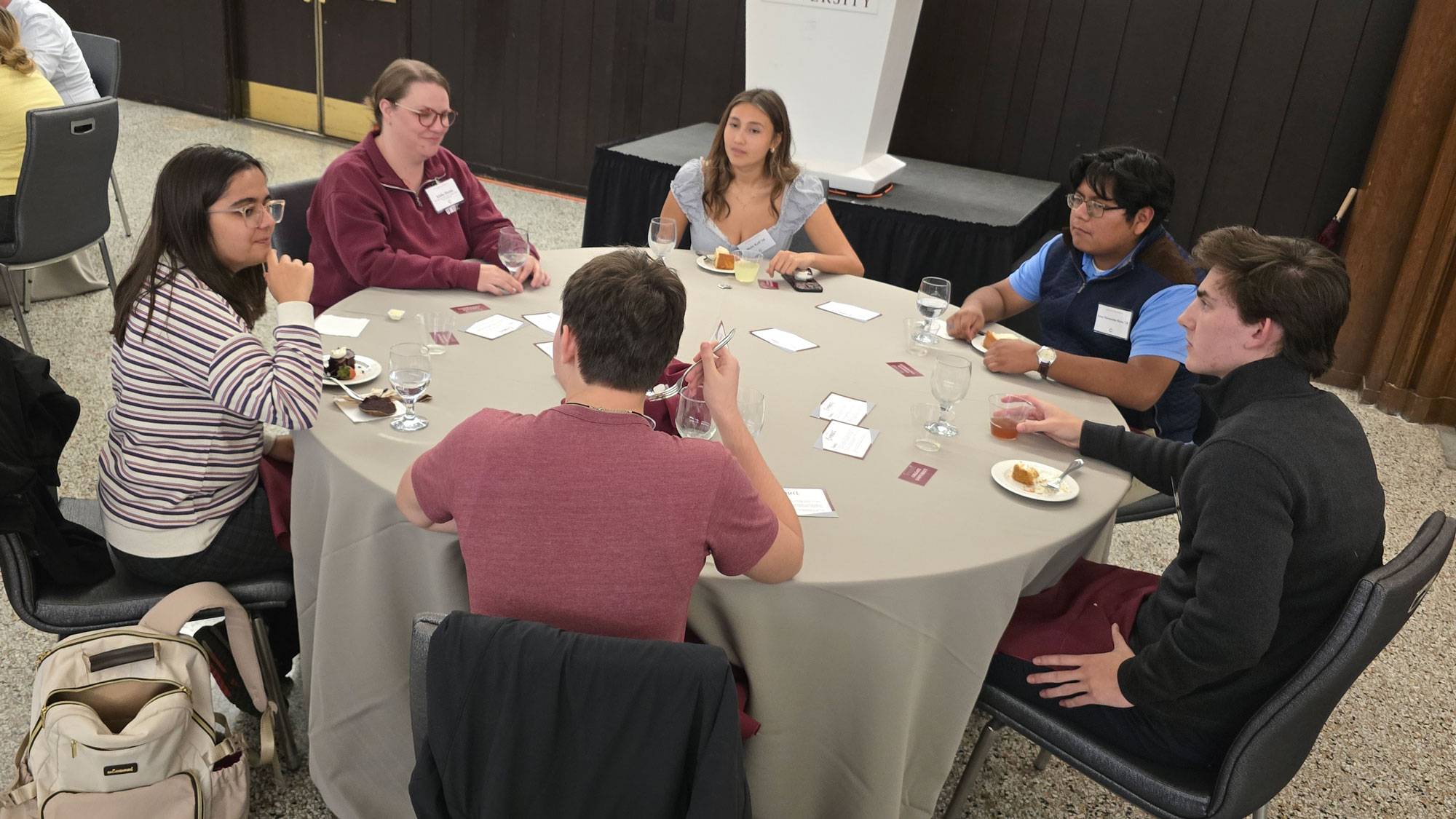 students, faculty members, and staff members sit around a table