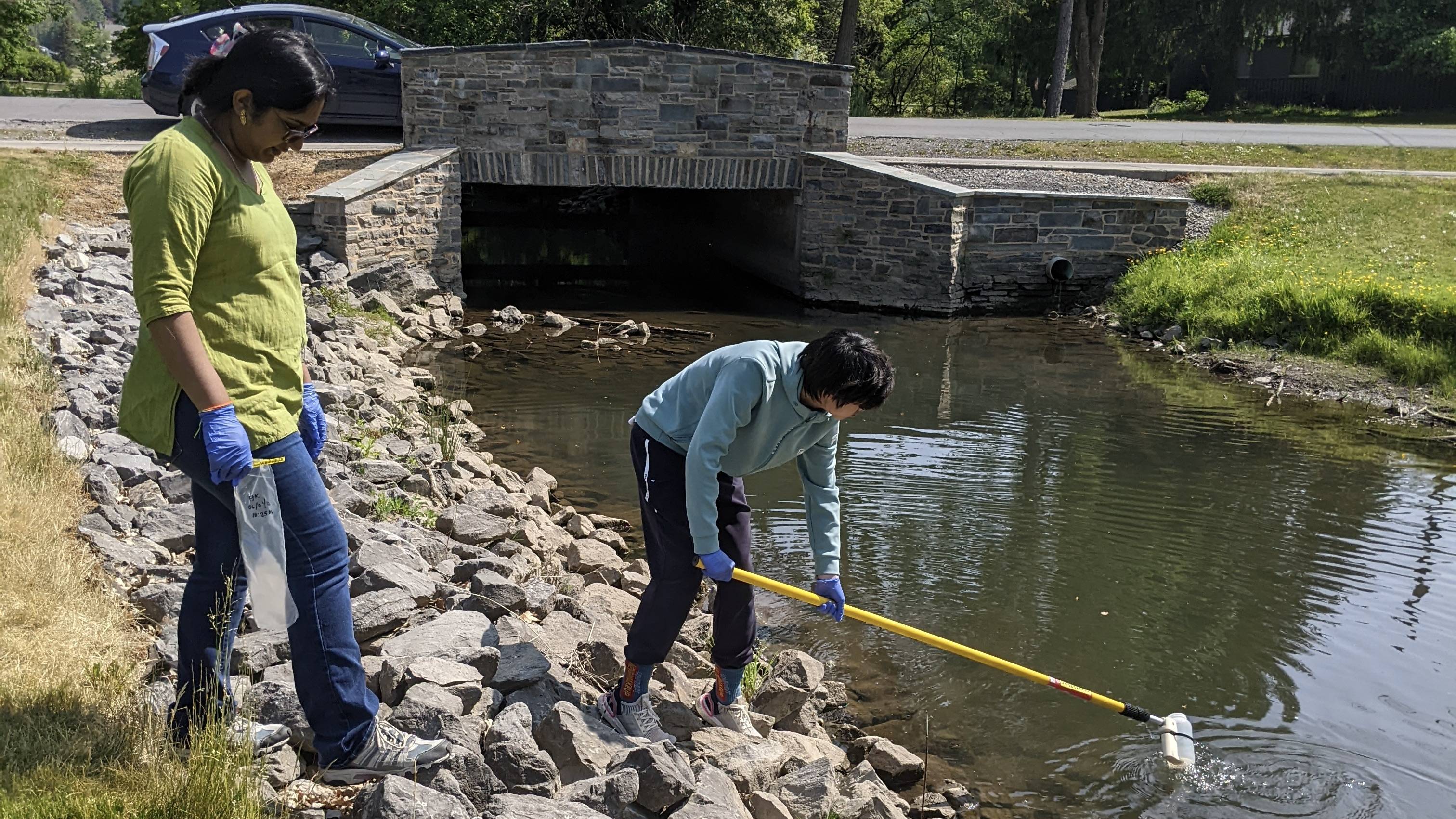 Researchers collect a water sample from a stream