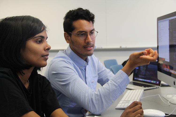 Students sit in front of a computer screen