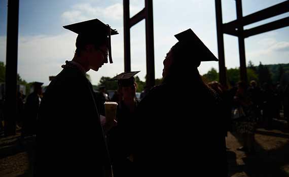 Students talking under the stands at Andy Kerr Stadium before commencement 2015