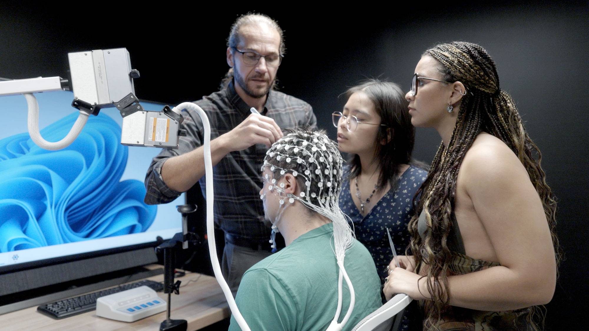 professor and students prepare subject for EEG