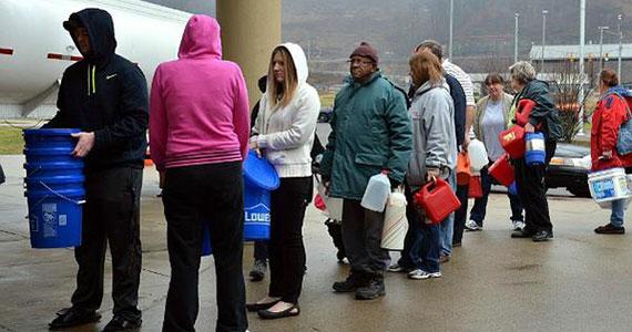 People wait to get water from a tanker truck at a high school near Charleston, W.Va. (Photo courtesy of Associated Press)