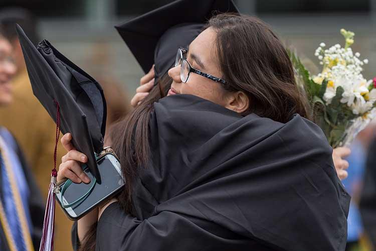Graduates hug after commencement 2018