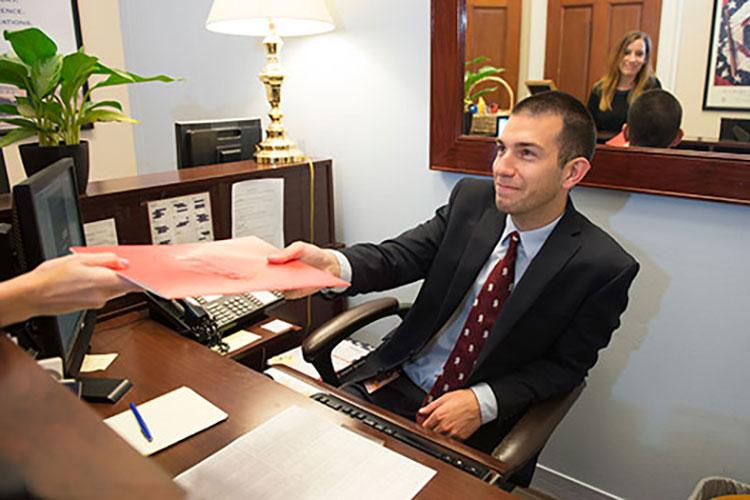 Kevin Costello ’16 hands a file across a desk in the office of Congressman Richard Hanna