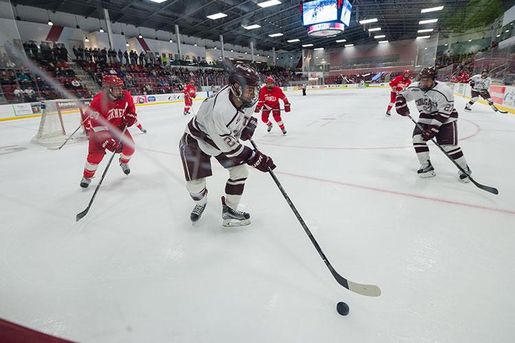 Colgate men's hockey player reaches out for puck in game against Cornell