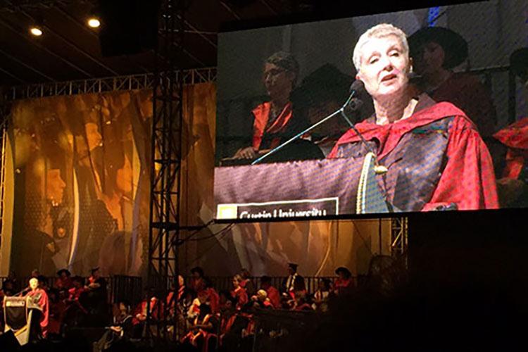 Professor Ellen Kraly stands at a podium, delivering the Occasional Address to graduating students at Australia's Curtin University